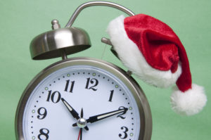 Running out of time before the holiday season.  Clock with santa hat in traditional red and green.